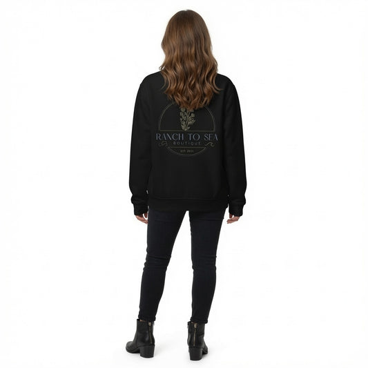 Crew neck fleece sweatshirt — black logo’d crew with gold and white Ranch To Sea Boutique graphic on the back, shown in AI lifestyle concept from behind with black skinny jeans and ankle boots (props not included) — results may vary, design image created using AI by RTS, see website for product details