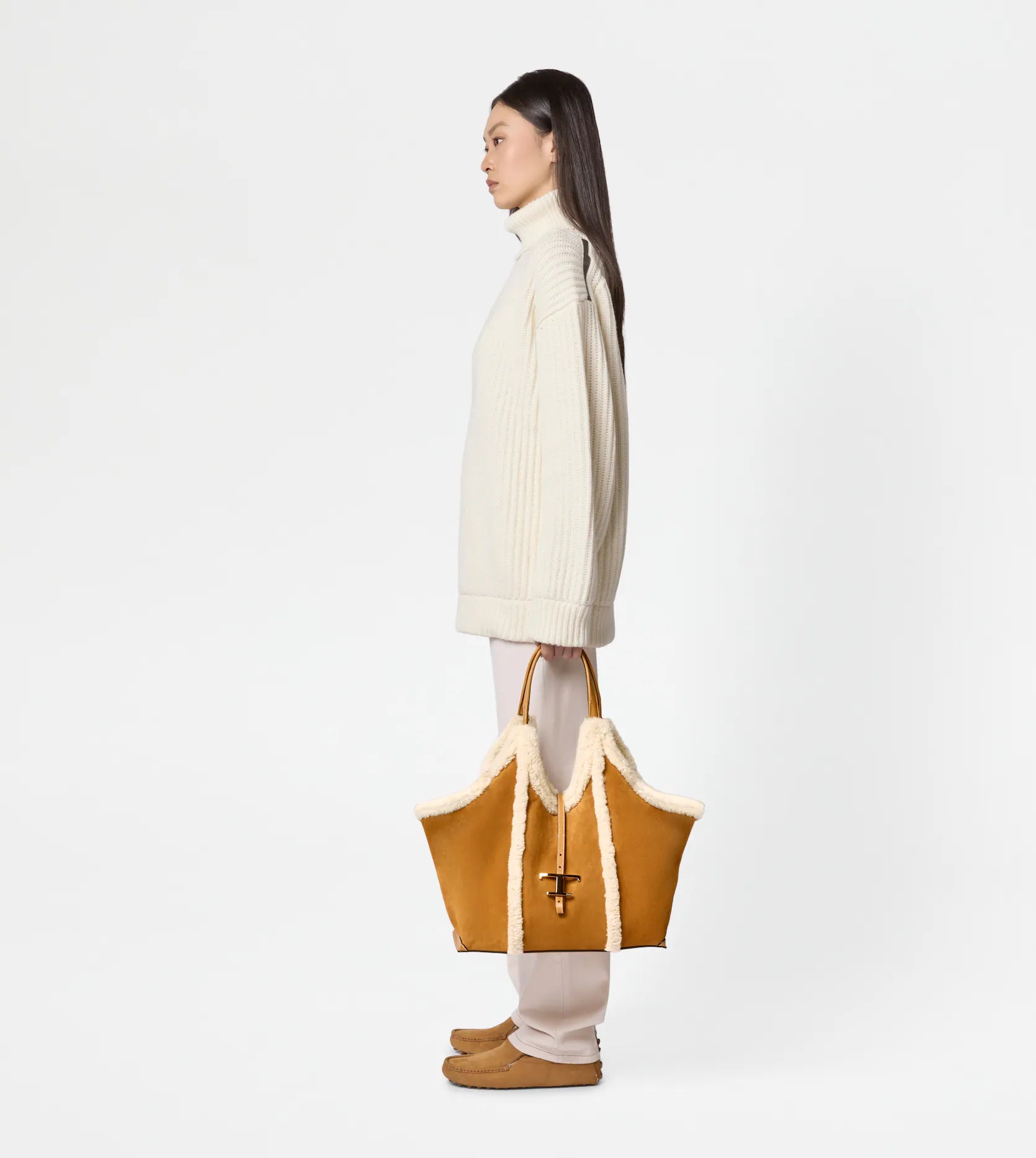Medium suede shopping bag with soft sheepskin piping being held by women side view for scale-