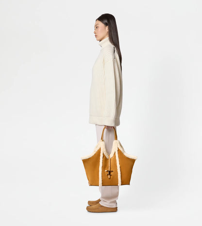 Medium suede shopping bag with soft sheepskin piping being held by women side view for scale-