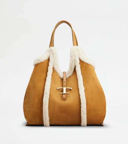 Medium suede shopping bag with soft sheepskin-Front view white backdrop- piping and metal T pendant Full front view with sides tucked in against white backdrop