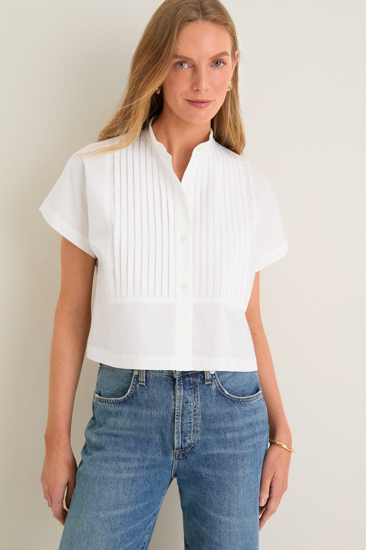 White pintuck shirt with short sleeves and cropped fit, worn with blue jeans