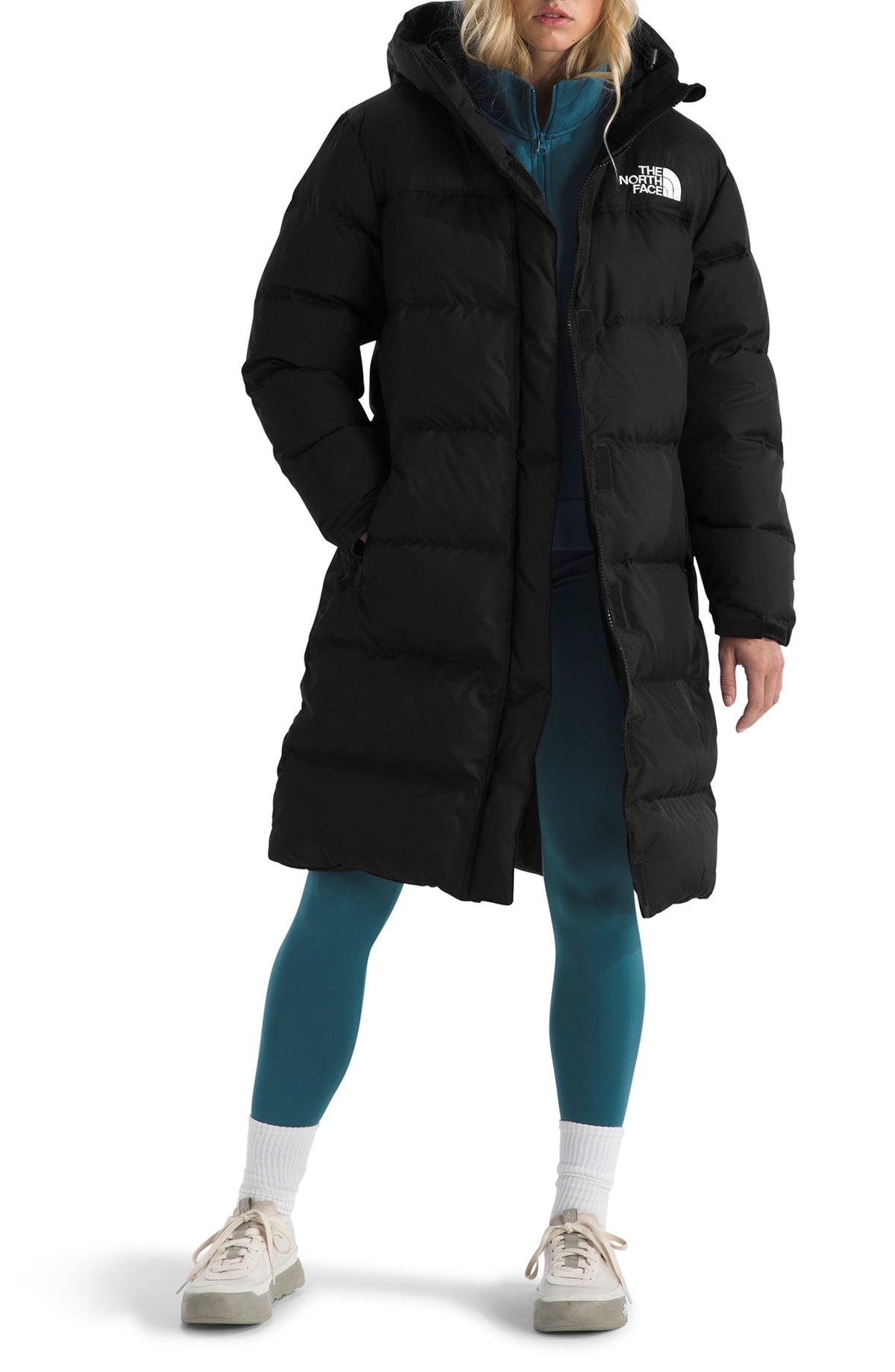Black long down puffer parka with hood, worn open over teal leggings, front view on model