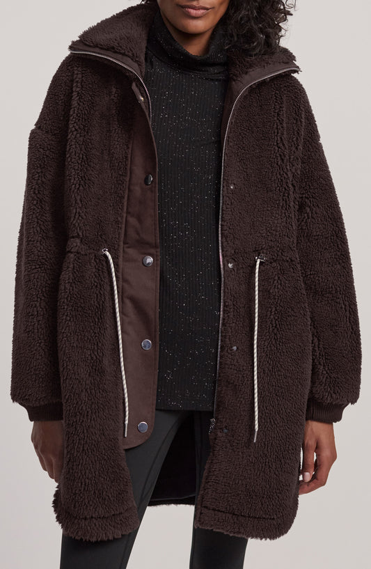 Dark brown high-pile fleece coat with drawcord waist and snap storm flap, front view on model