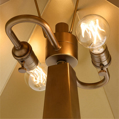 Close-up of a brass geometric floor lamp two lit bulbs on a beige background