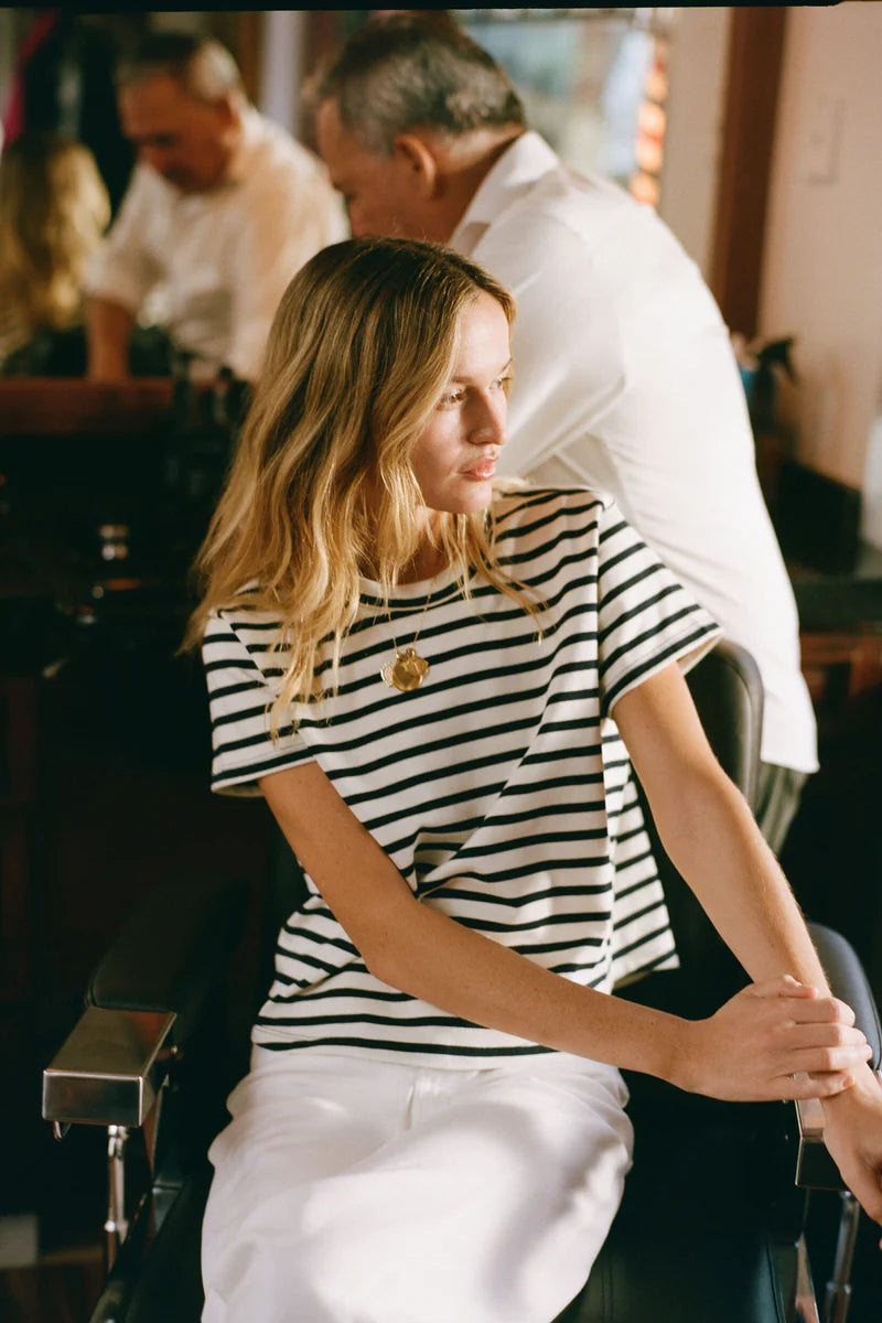 classic striped crewneck tee, model  in a striped shirt sitting in a chair with a man standing behind her.