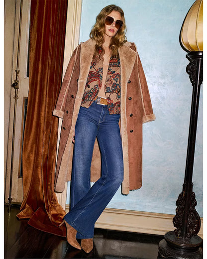 Engraved buckle western belt  model wearing a long brown coat, patterned top, and blue jeans indoors.
