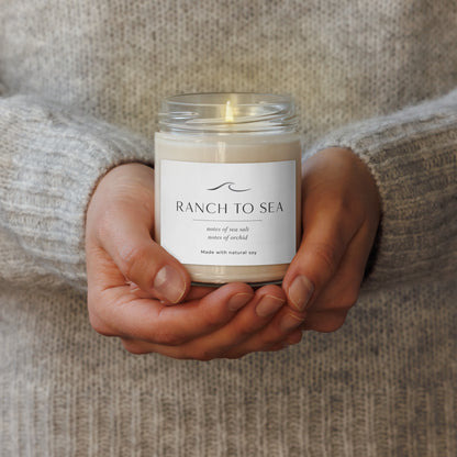 Person in oatmeal fishermans sweater holding after the fog natural soy candle