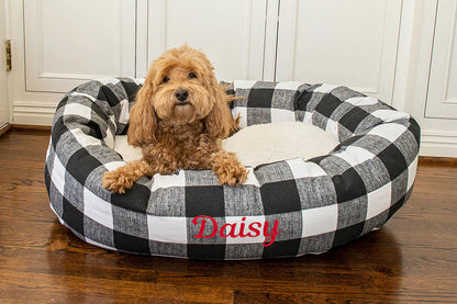 Dog lying on a checkered pet bed with embroidered name on it, in a home setting washable pet bed